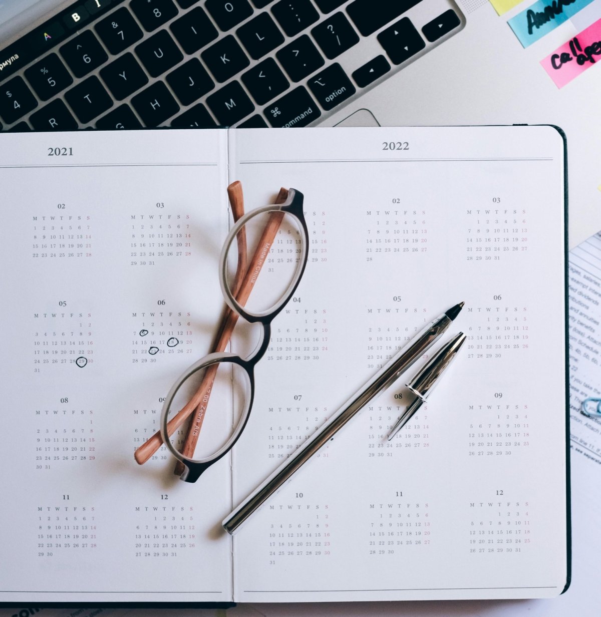 Agenda annuel ouvert, lunettes et stylos posés dessus